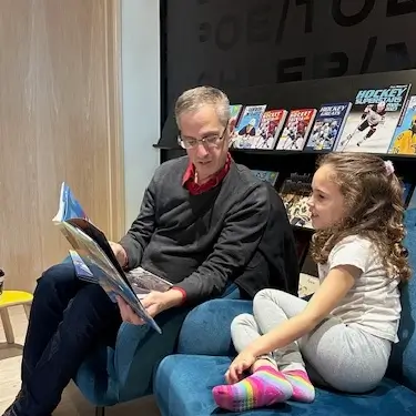 Maestro Robert Franz reading to a young girl