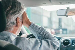 older driver with hand on head from stress