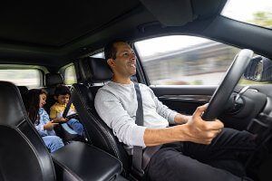 driver with kids in the backseat looking at ipad