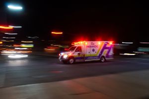 ambulance in intersection, lights on at night
