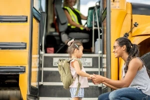 A parent sending their child on a school bus.